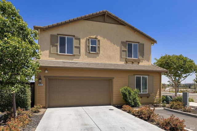 traditional-style house with driveway, stucco siding, a tiled roof, and a garage