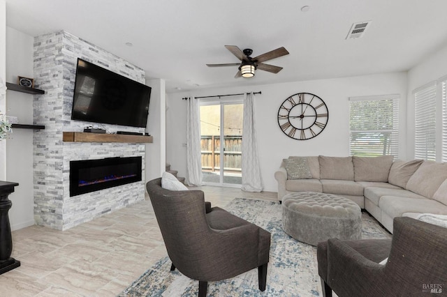 living area with visible vents, a fireplace, a ceiling fan, and a healthy amount of sunlight