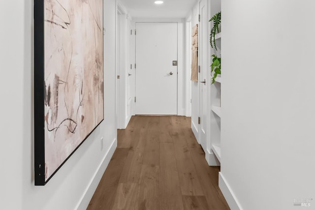 hall with baseboards and wood finished floors