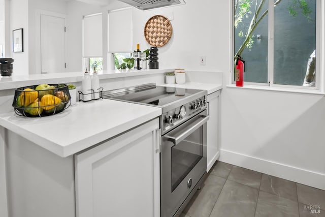 kitchen featuring tile patterned floors, a wealth of natural light, stainless steel range, and light countertops