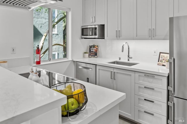 kitchen with a sink, backsplash, light countertops, and appliances with stainless steel finishes