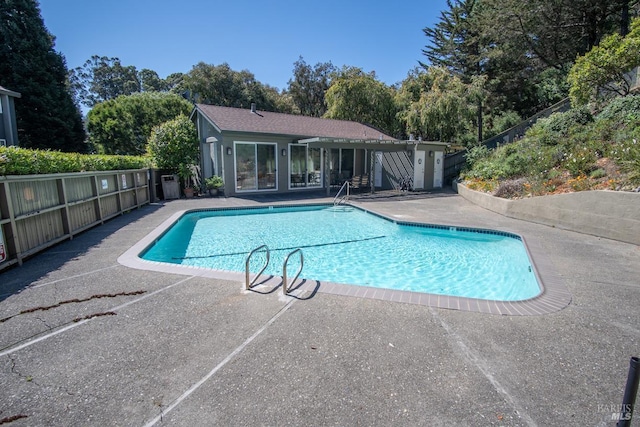 community pool with a patio area and fence