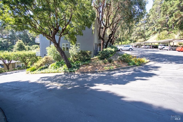 view of side of home featuring covered and uncovered parking and stucco siding