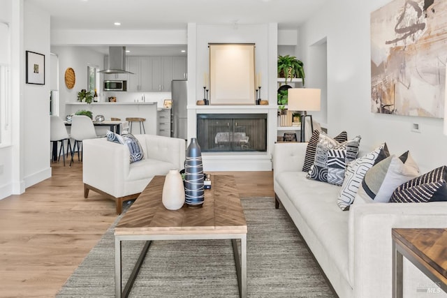 living area featuring baseboards, recessed lighting, a fireplace, and light wood-type flooring
