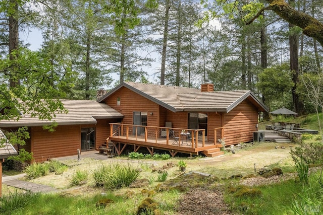 rear view of property featuring a chimney and a wooden deck