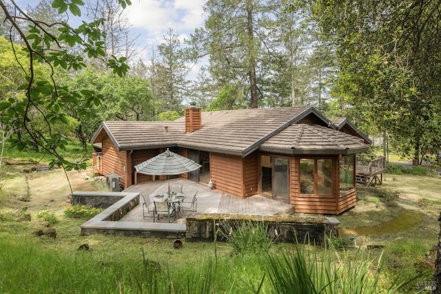 rear view of property featuring a chimney and a wooden deck