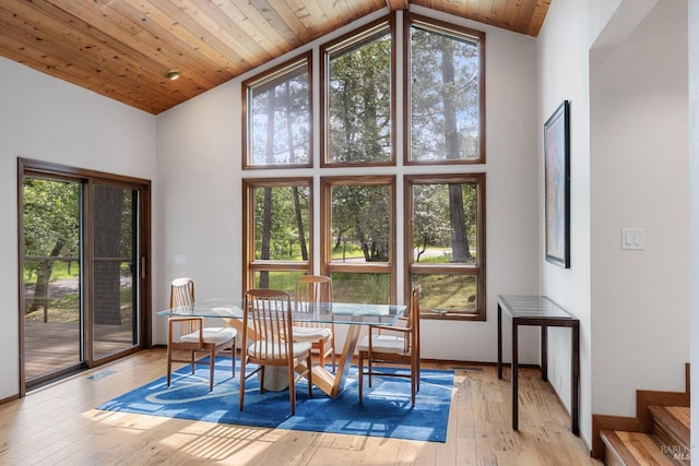 dining space featuring wooden ceiling, wood-type flooring, a wealth of natural light, and high vaulted ceiling