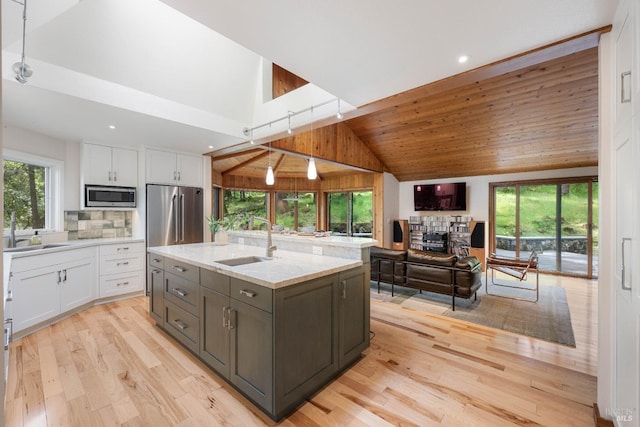 kitchen with open floor plan, appliances with stainless steel finishes, a sink, and white cabinets