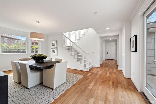dining area featuring baseboards, stairs, ornamental molding, and light wood finished floors