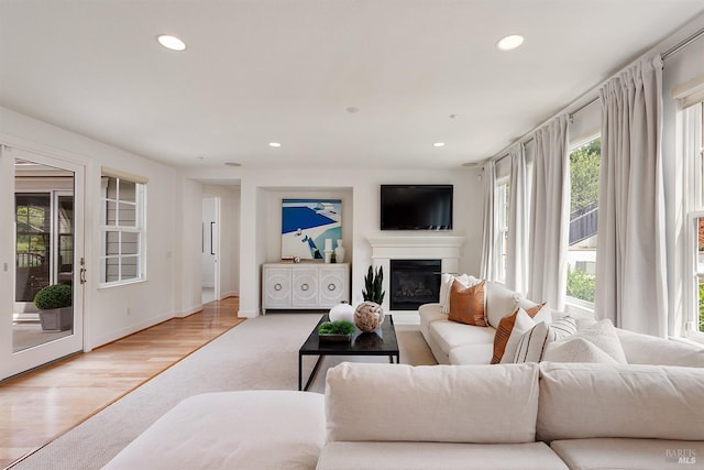 living area featuring a glass covered fireplace, recessed lighting, and light colored carpet