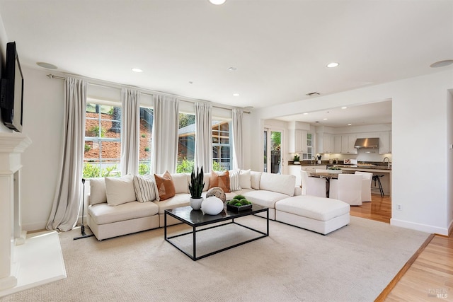 living area featuring light wood-type flooring, visible vents, baseboards, and recessed lighting