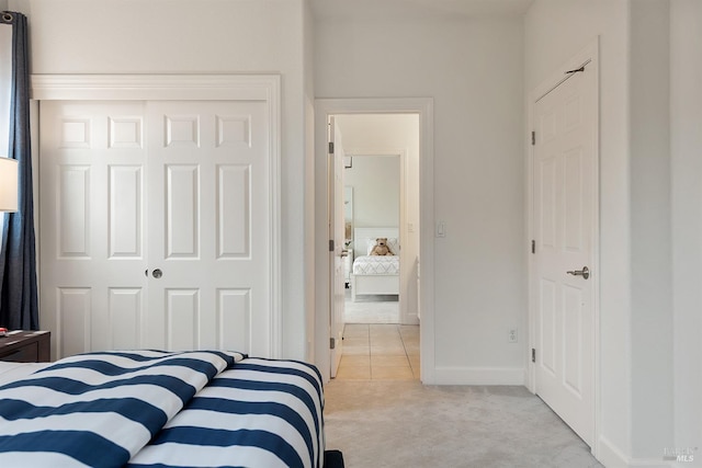 bedroom featuring light colored carpet, a closet, and baseboards