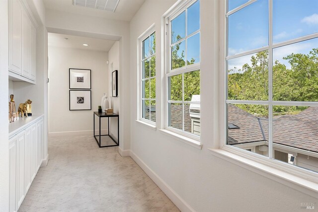 hall with light colored carpet, baseboards, and visible vents