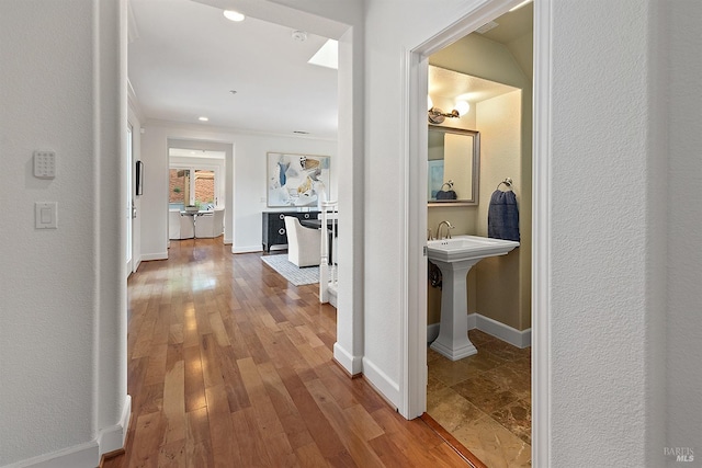 hallway featuring crown molding, wood finished floors, and baseboards