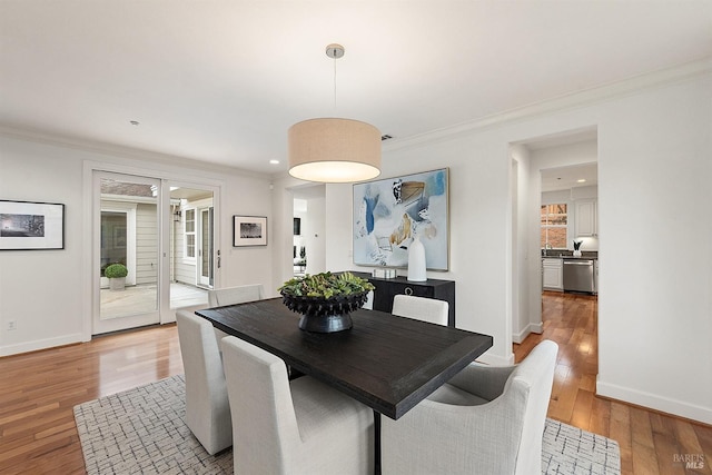 dining space featuring light wood-style flooring, crown molding, plenty of natural light, baseboards, and recessed lighting