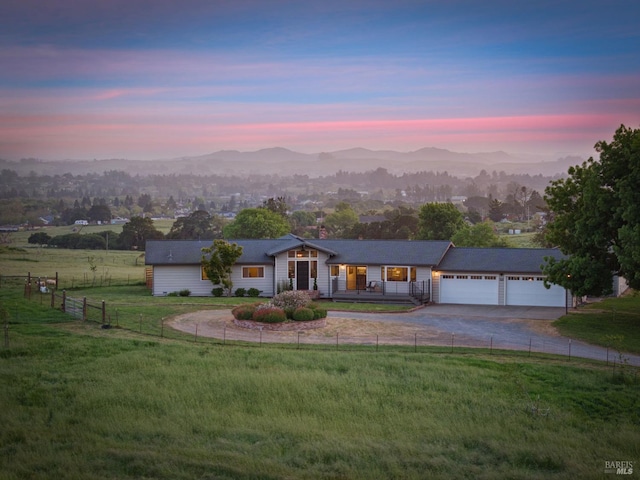 ranch-style house with concrete driveway, a mountain view, a garage, and a front lawn