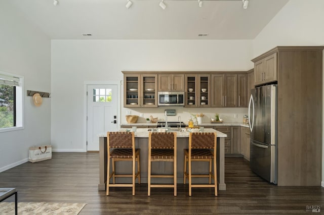 1568 Old Adobe Rd, Petaluma, CA 94954 - kitchen with stainless steel appliances, dark wood-style flooring, a center island with sink, glass insert cabinets, and a kitchen bar