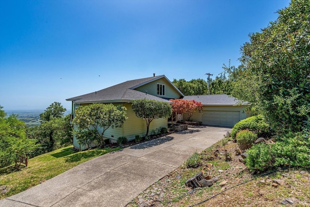 view of front of house with an attached garage, concrete driveway, and a shingled roof