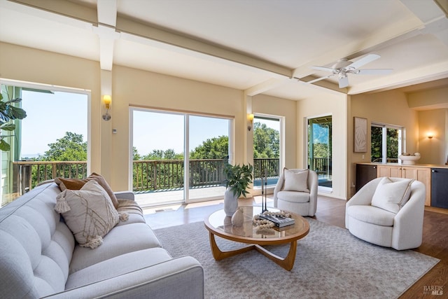 living area featuring a ceiling fan, beam ceiling, and wood finished floors