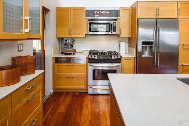 kitchen featuring appliances with stainless steel finishes, glass insert cabinets, and dark wood-style flooring