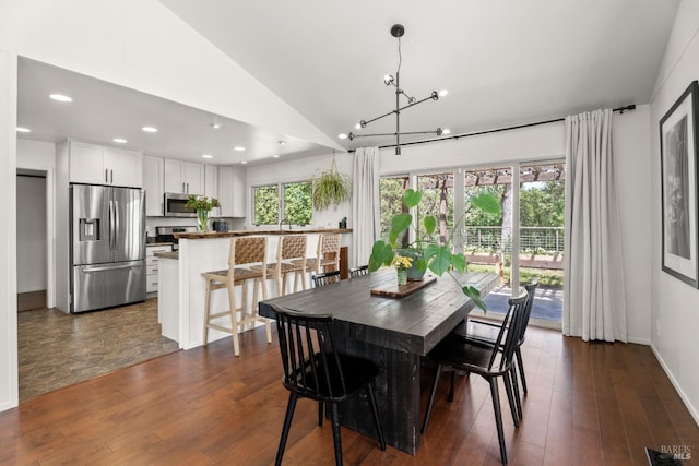 dining space with recessed lighting, lofted ceiling, dark wood-style floors, and a notable chandelier