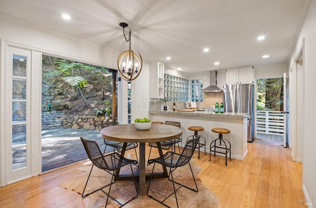 dining space featuring crown molding, light wood-style flooring, a notable chandelier, and recessed lighting