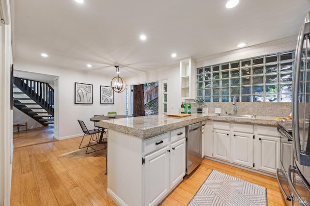 kitchen featuring recessed lighting, dishwasher, a sink, a peninsula, and white cabinets
