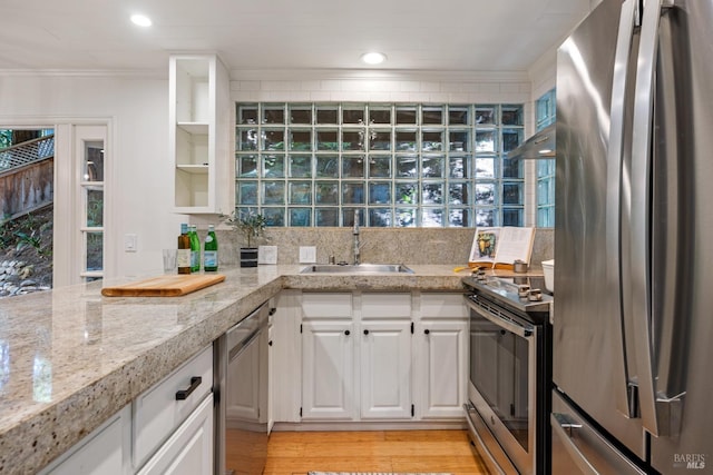 kitchen with a sink, stainless steel appliances, crown molding, white cabinetry, and under cabinet range hood