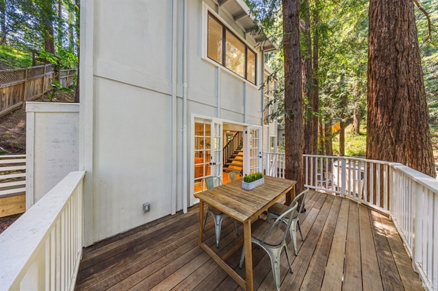 wooden terrace with french doors, outdoor dining area, and fence