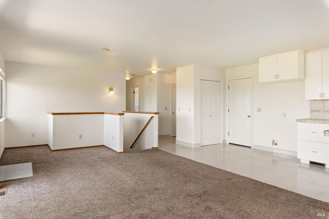 unfurnished room featuring light tile patterned floors, light carpet, and baseboards