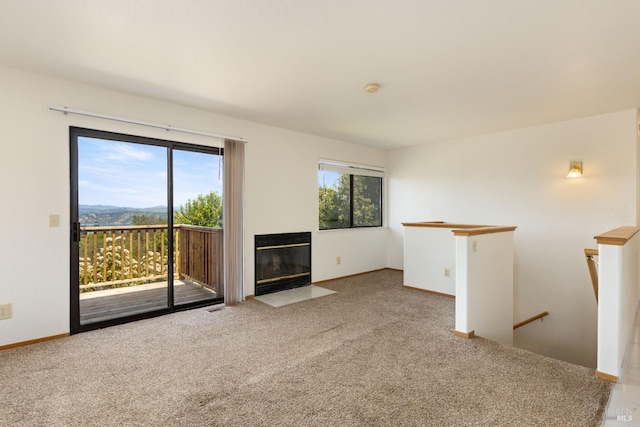 unfurnished living room featuring baseboards, a fireplace with flush hearth, and carpet floors