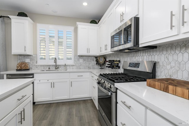 kitchen with a sink, stainless steel appliances, dark wood finished floors, white cabinetry, and decorative backsplash