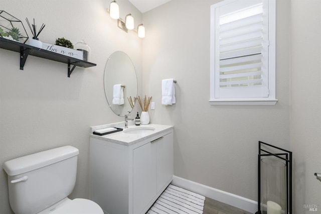 half bathroom featuring vanity, toilet, and baseboards