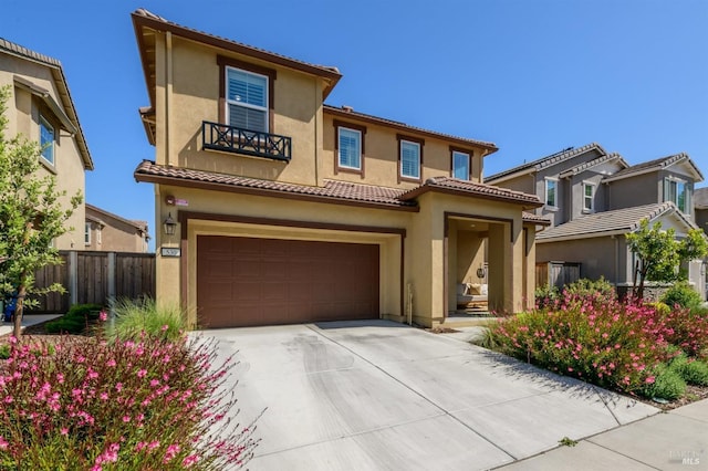 view of front of house featuring fence, a tile roof, concrete driveway, a garage, and stucco siding