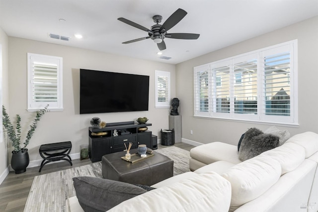 living room featuring wood finished floors, visible vents, baseboards, and a ceiling fan