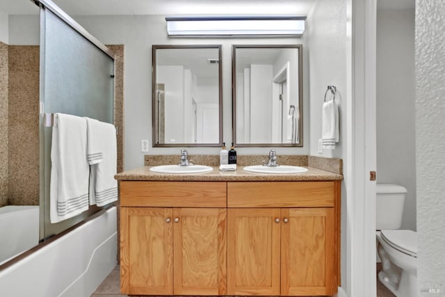 full bath with toilet, combined bath / shower with glass door, double vanity, and a sink