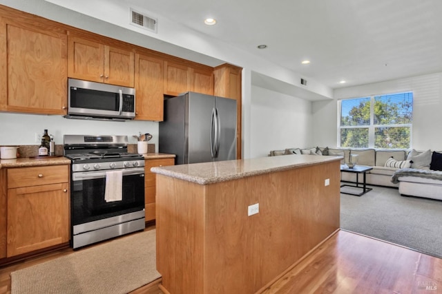 kitchen with light wood-style flooring, open floor plan, visible vents, appliances with stainless steel finishes, and a kitchen island