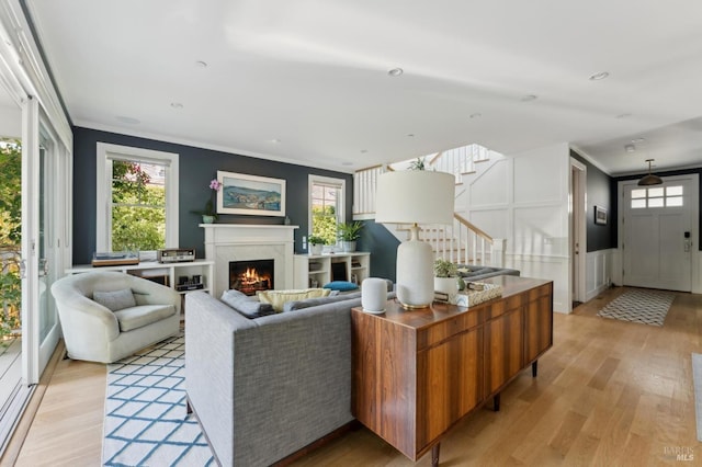 11 Heather Way, Larkspur, CA 94939 - living room with stairway, light wood-style floors, crown molding, a warm lit fireplace, and plenty of natural light