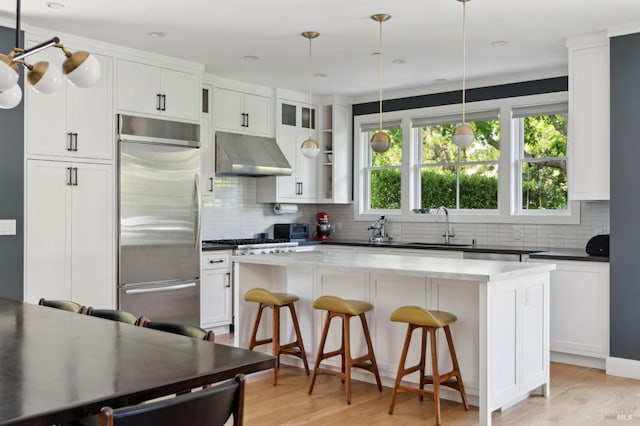11 Heather Way, Larkspur, CA 94939 - kitchen with appliances with stainless steel finishes, under cabinet range hood, decorative backsplash, a center island, and white cabinetry