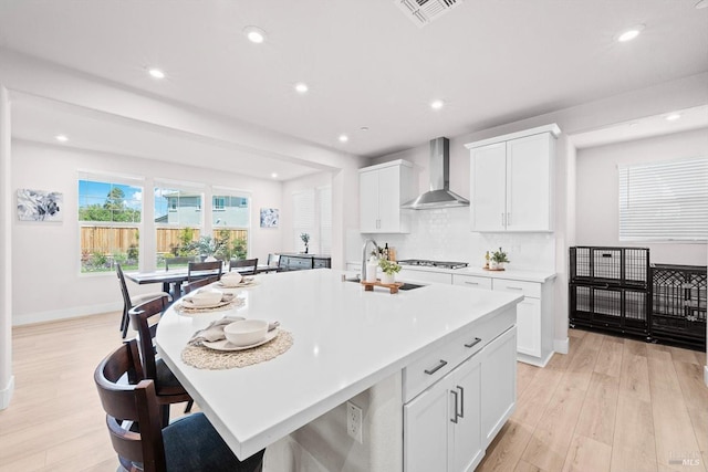 1532 Base Ct, Dixon, CA 95620 - kitchen with light countertops, light wood-style flooring, a sink, white cabinetry, and wall chimney range hood