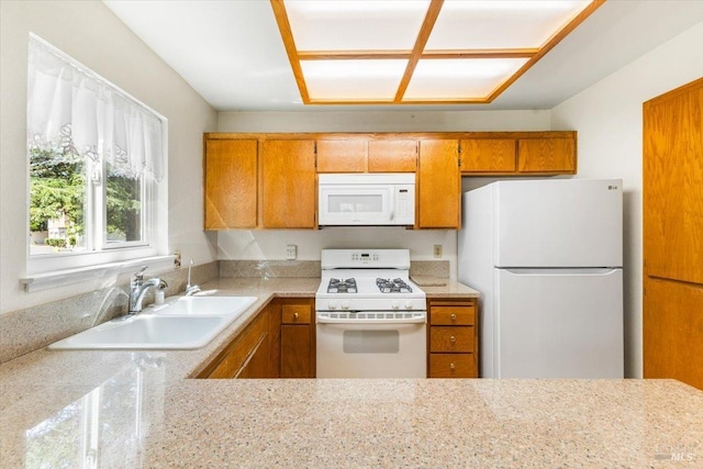 kitchen with brown cabinets, a sink, and white appliances