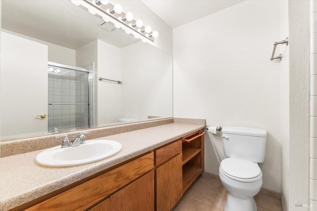 bathroom with toilet, baseboards, a tile shower, tile patterned floors, and vanity