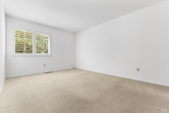 spare room with baseboards and light carpet