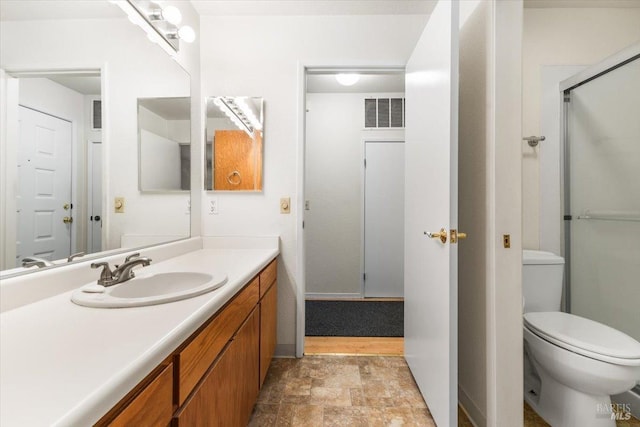 bathroom with toilet, vanity, visible vents, an enclosed shower, and stone finish flooring