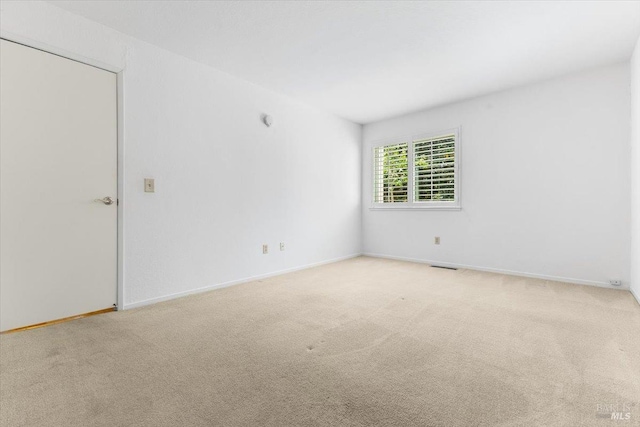spare room featuring baseboards, visible vents, and carpet floors