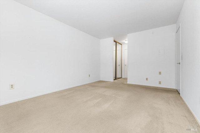 spare room with light colored carpet and baseboards