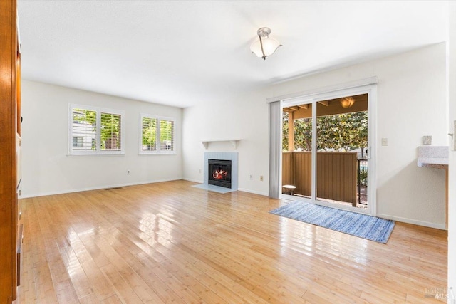 unfurnished living room with visible vents, light wood-style flooring, baseboards, and a fireplace with flush hearth