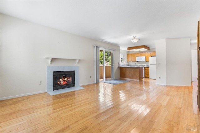unfurnished living room with baseboards, light wood-style floors, and a fireplace with flush hearth