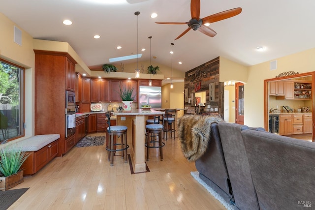 kitchen with a ceiling fan, a kitchen bar, open floor plan, built in appliances, and light countertops