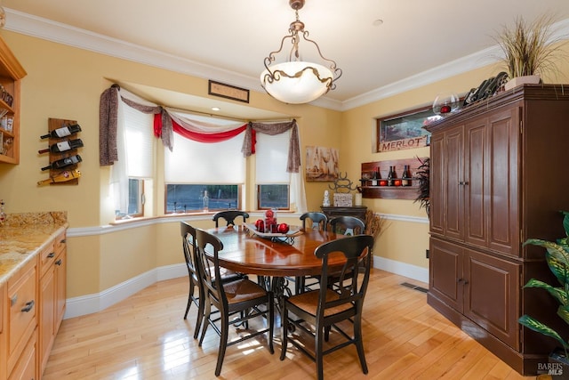 dining space featuring ornamental molding, baseboards, light wood-type flooring, and visible vents